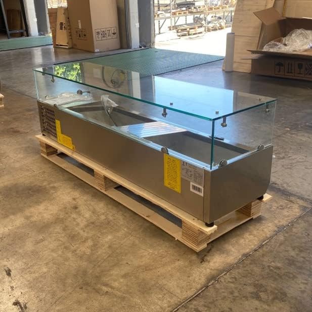 Side view of the cooler depot VRX1500 refrigerated countertop preparation table on a wooden pallet, showing the compressor side.