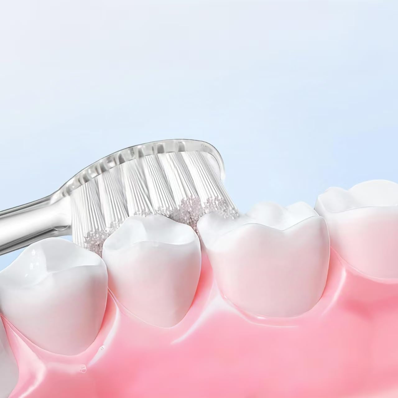 Close-up image of a toothbrush head brushing teeth, showing bristles reaching between teeth.
