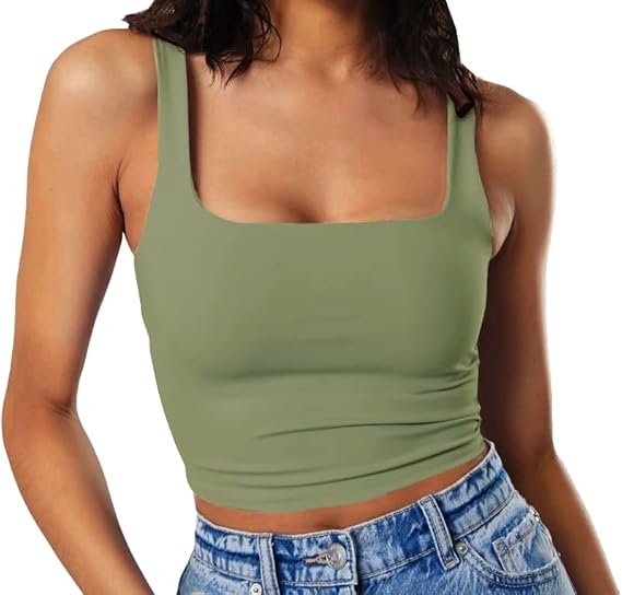 A woman with black hair wearing a green tank top and jean shorts
