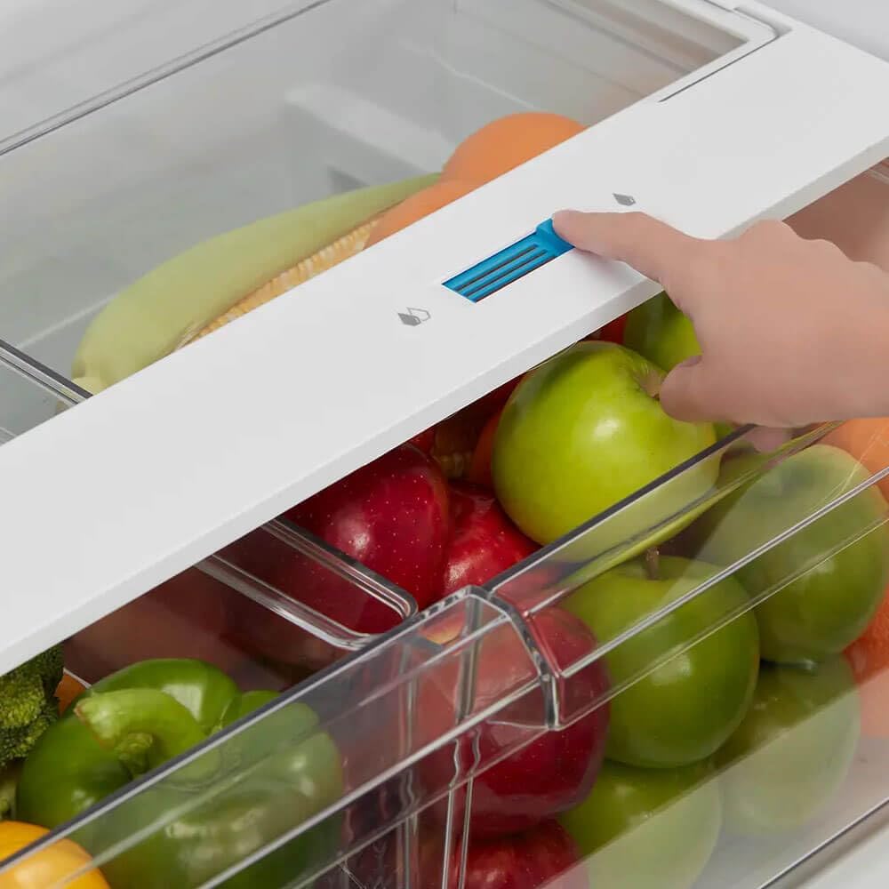 Hand adjusting the humidity slider on a crisper drawer inside the refrigerator