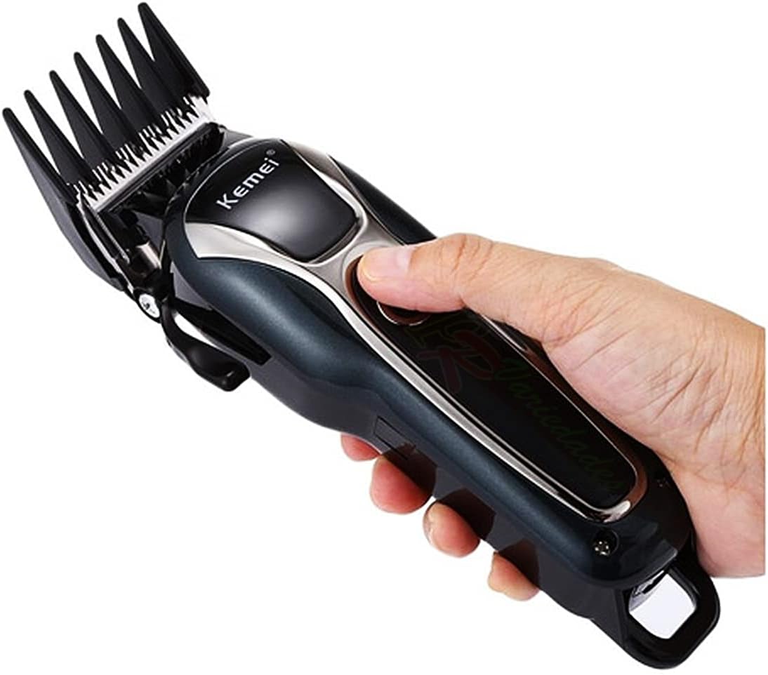 A hand holding the Kemei KM-1991 Pet Grooming Machine with a comb attached, demonstrating how it is held during use.