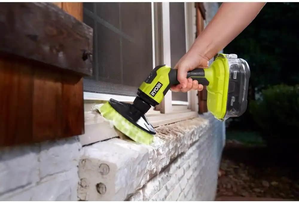 RYOBI ONE+ 18V Cordless Compact Power Scrubber being used to clean a window sill outdoors.