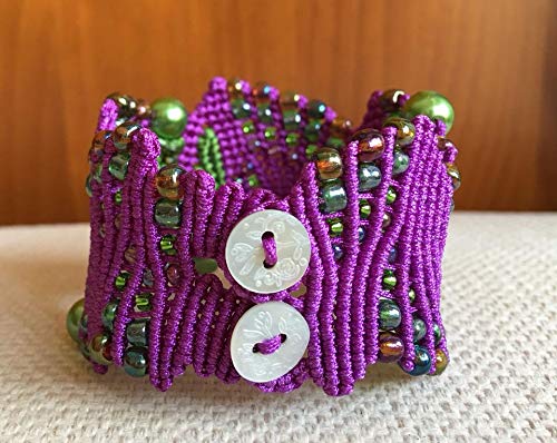 Pulsera macramé hecha a mano con hilo púrpura y verde Cierra con dos botones de nacar. Mide aprox. 16,5 cm. de largo