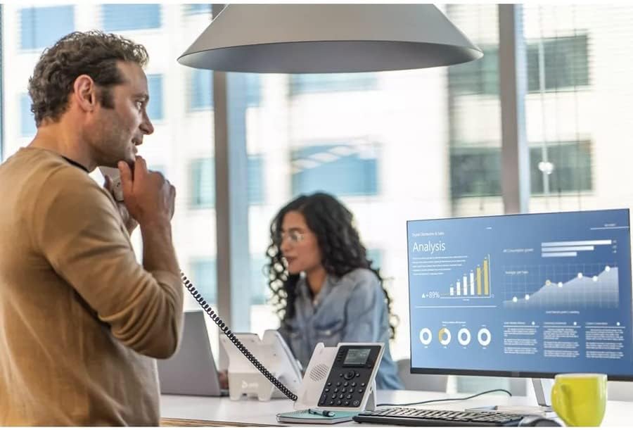 Muž používající stolní telefon Poly Edge E220 IP v kancelářském prostředí