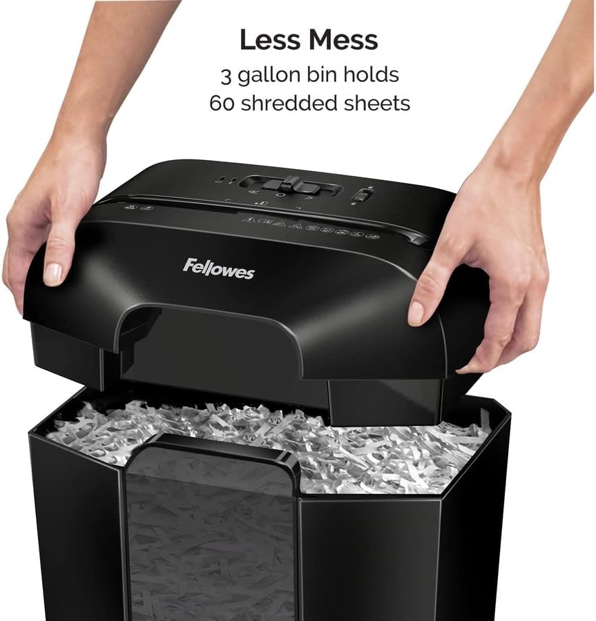 Hands lifting the top of the Fellowes LX25 shredder to reveal the waste bin filled with shredded paper
