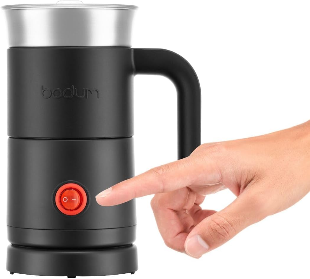 Hand pressing the power button on the Bodum Barista Electric Milk Frother