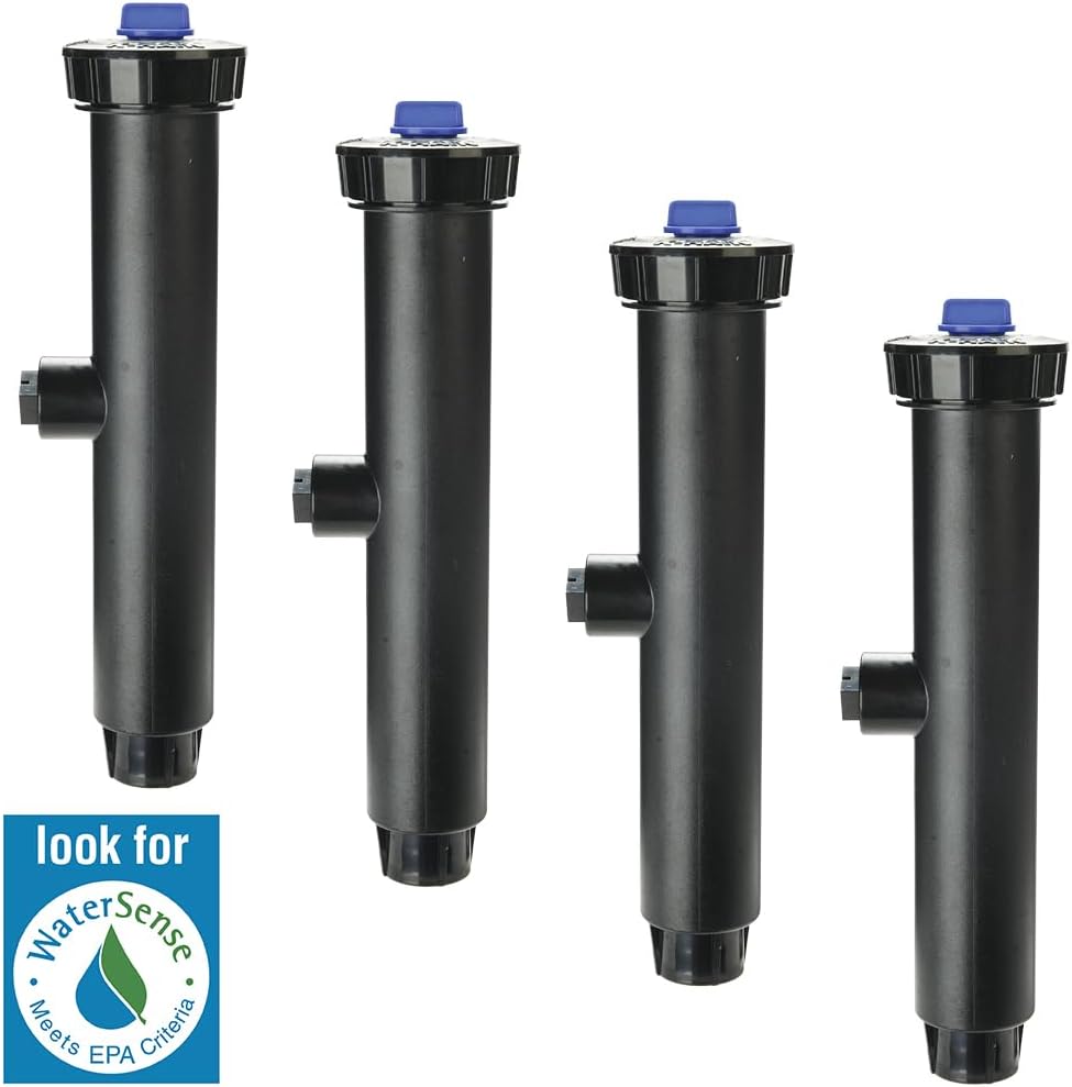 A K-Rain Pro-S pop-up spray head with a blue cap, partially submerged in green grass, spraying water. The image shows the spray pattern and the head's position in the lawn.