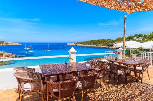 adrium Holz-Bild 120 x 80 cm: Tische mit Stühlen auf der Terrasse des Küstenrestaurants in der Bucht von Cala Portinatx, Insel Ibiza, Spanien. (93345367)