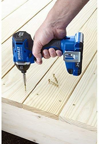 A hand holding the Kobalt impact driver, driving a screw into a wooden board.
