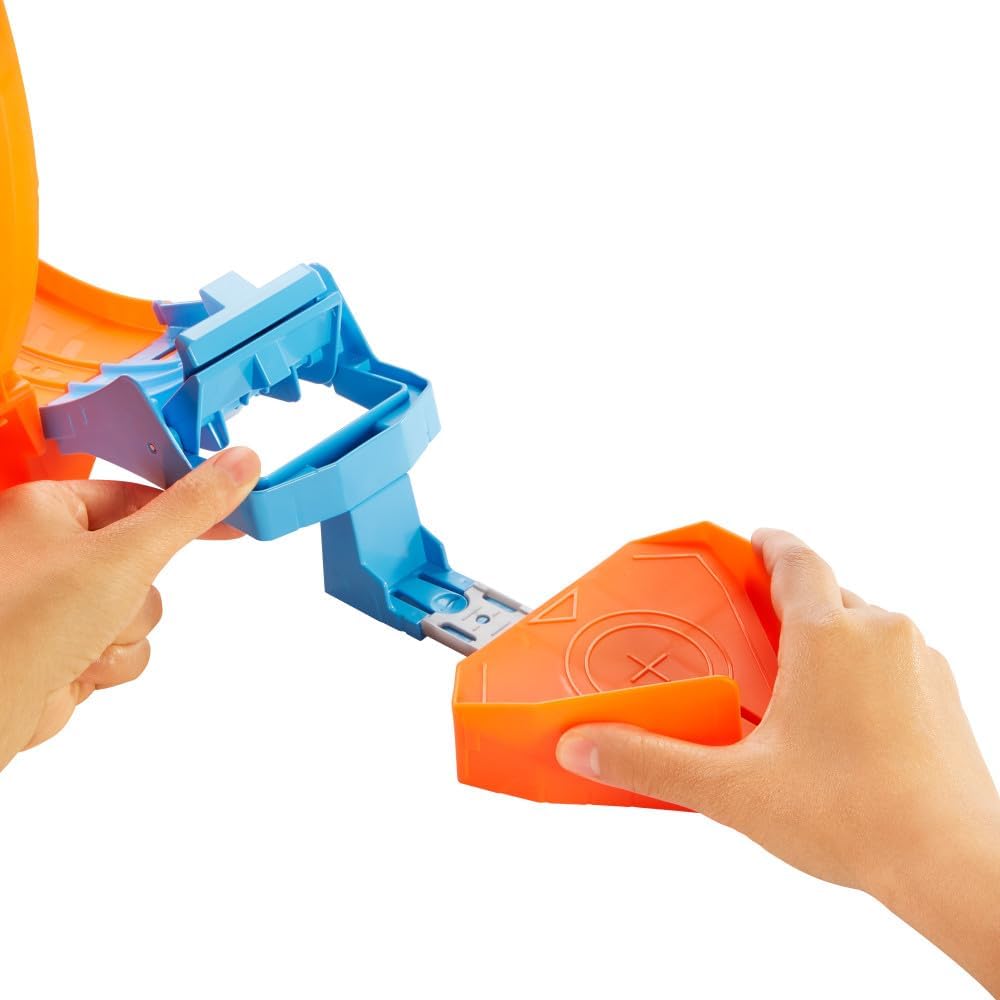 Hands connecting two parts of the Hot Wheels track set.
