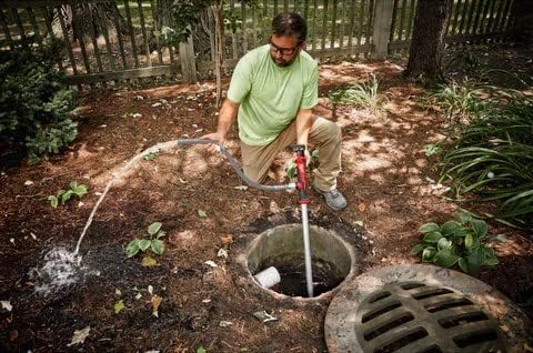 Person using the Milwaukee M12 Stick Transfer Pump to drain a catch basin