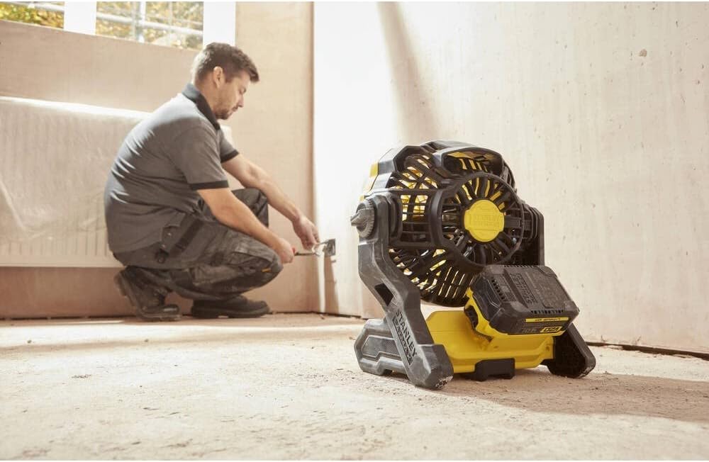 Man positioning STANLEY SFMCE001B-XJ V20 Li-Ion 18V Cordless Fan on a floor