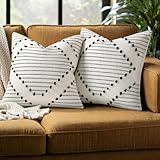 Style bohème et ferme : ces housses de coussin noires et blanc crème sont tissées avec des pompons noirs et un tissu de base blanc crème. Les motifs simples et neutres donnent à ces housses de coussin texturées tricotées un style moderne et bohème