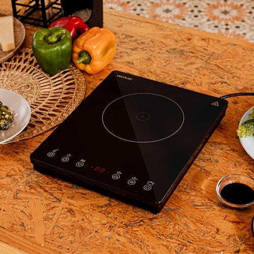 Placa de inducción Cecotec en una mesa con varios ingredientes frescos alrededor