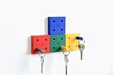 DESIGN MODULAIRE COLORÉ: Ensemble de 4 blocs muraux en forme de dés aux couleurs vives (rouge, jaune, vert, bleu) qui s'assemblent pour créer un porte-clés décoratif et fonctionnel