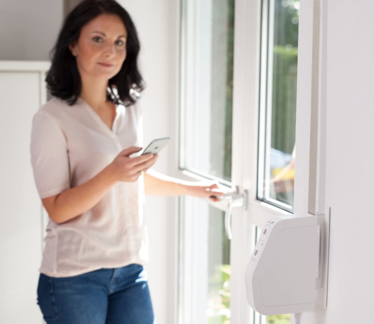 Woman using a smartphone app to control a Schellenberg roller shutter winder