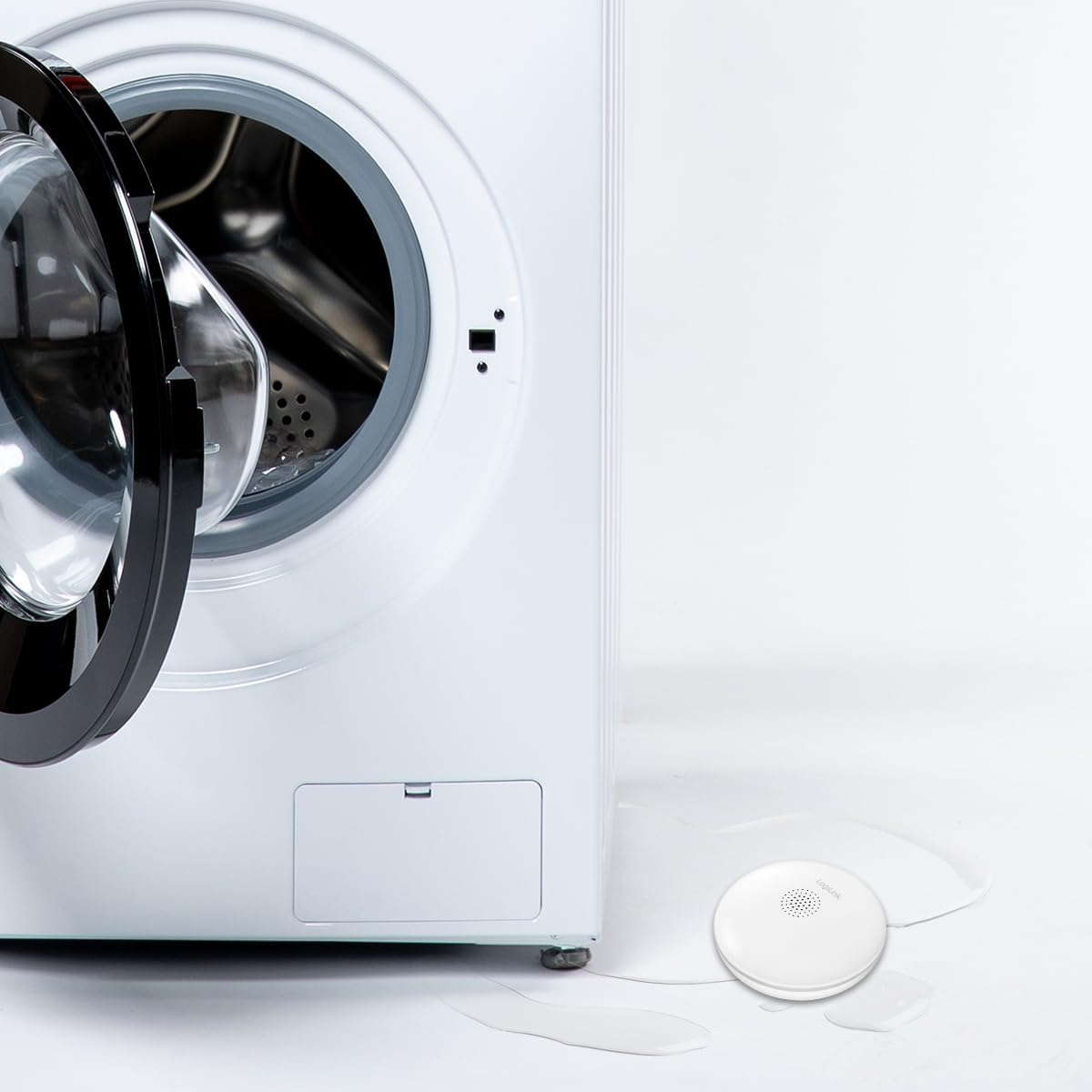 LogiLink SH0134 Water Leak Sensor placed on the floor next to a washing machine with a small water leak.