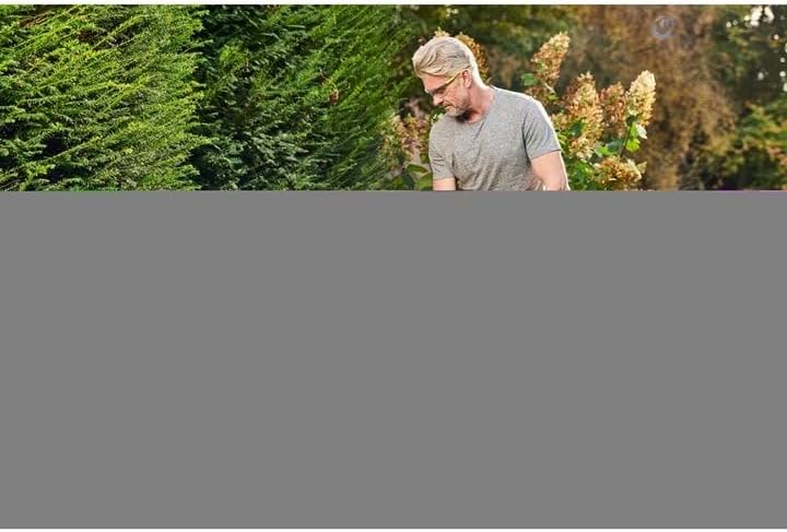 Person using RYOBI grass trimmer to trim grass in a garden