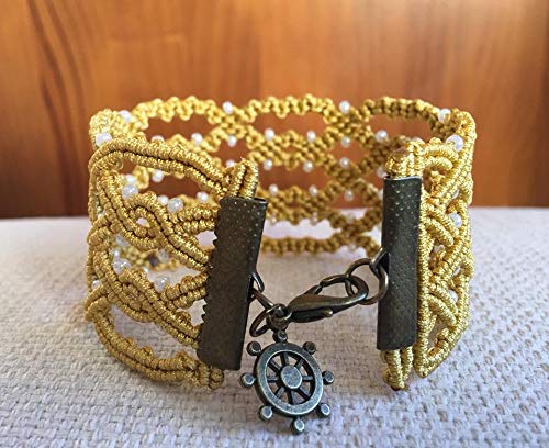 Pulsera macrame celta hecha a mano con hilo dorado.Mide aprox.19 cm. de largo y 3,5 cm.de ancho .Cierre y adorno colgalte.