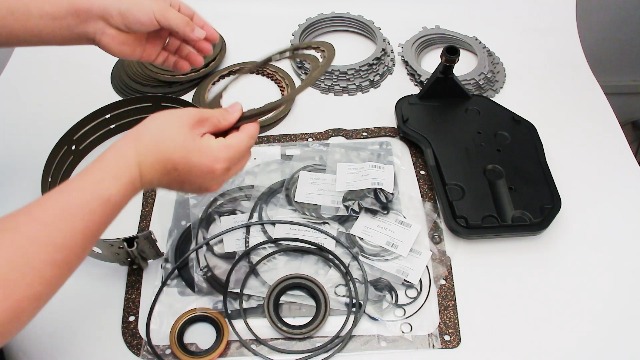 Various 4L60E transmission rebuild kit components laid out on a white surface