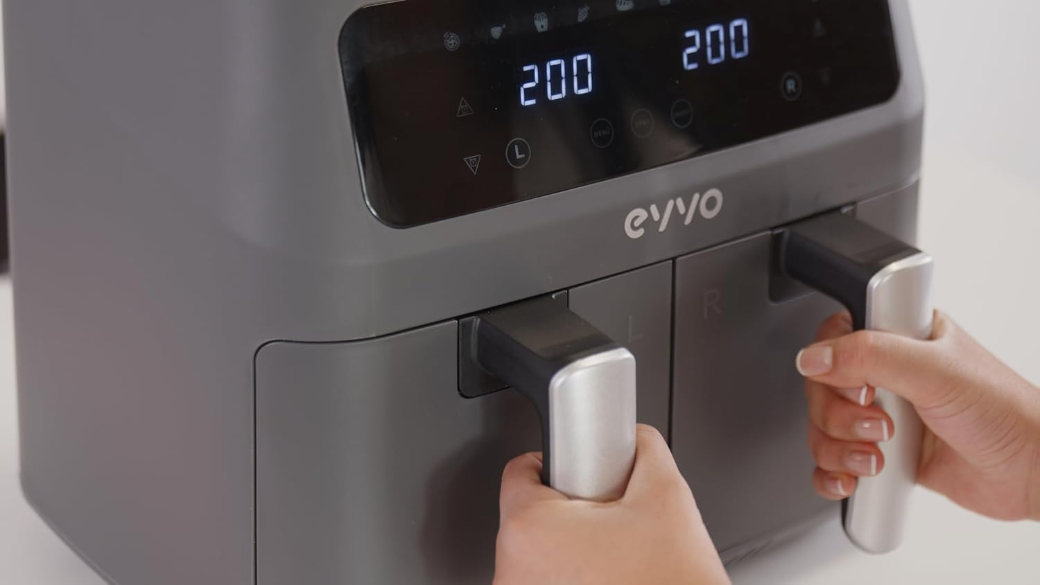 Hands pulling out air fryer baskets