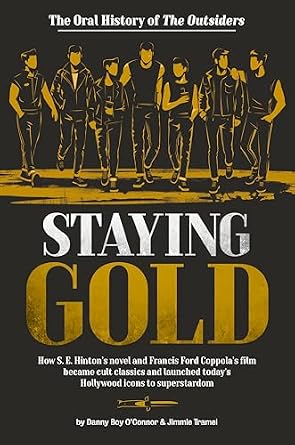 Staying Gold by Danny Boy O'Connor, a film history piece has the cast of the story illuminated in gold against a black background, also walking on a gold walkway. The title is big with "staying" in white and "gold" in gold.