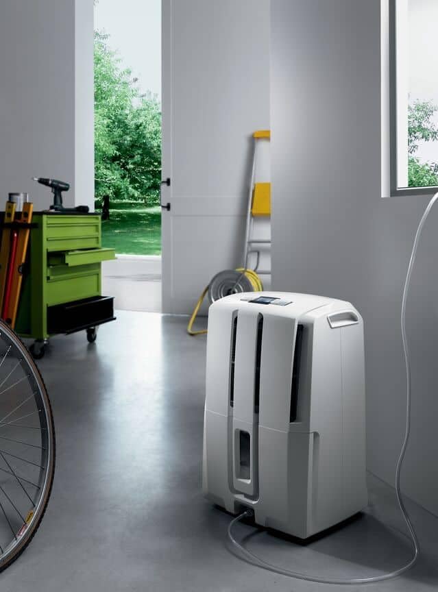 De'Longhi DD230P Dehumidifier placed in a room with a drainage hose connected