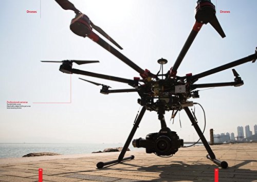 A large professional drone with a camera mounted underneath, standing on a paved area near water.