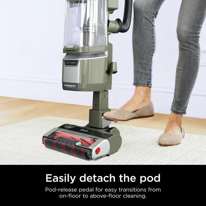 A foot pressing the pedal to detach the vacuum pod from the floor nozzle.