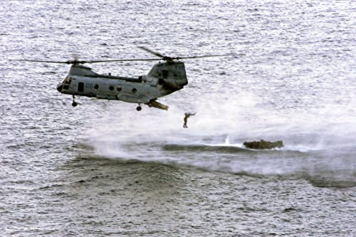 A US Marine Corps (USMC) CH-46 Sea Knight helicopter drops swimmers near their Rigid Hull Inflatable Boat (RHIB), while conducting helicopter casting operating - 12 Inch by 18 Inch Laminated Poster - Bright Colors And Vivid Imagery