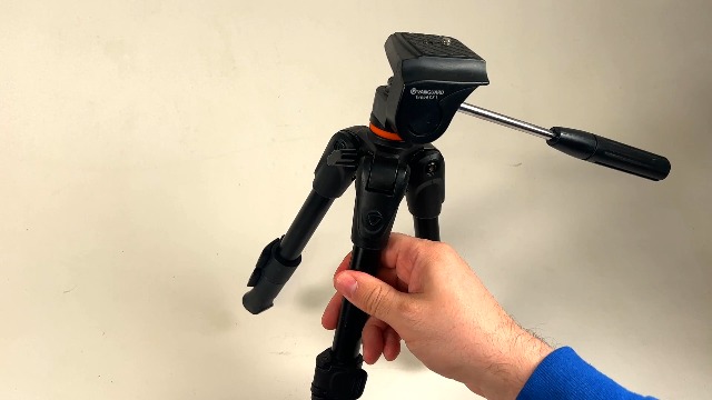 Hands adjusting the VANGUARD Espod CX 1 Tabletop Tripod, showing leg extension and head adjustment.