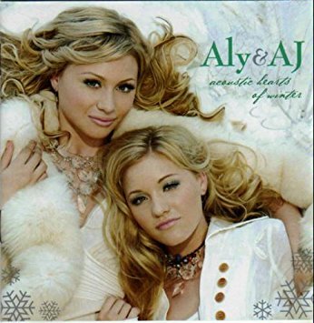 Aly & AJ's Acoustic Hearts of Winter. Aly and AJ in front of snowy background wearing white.