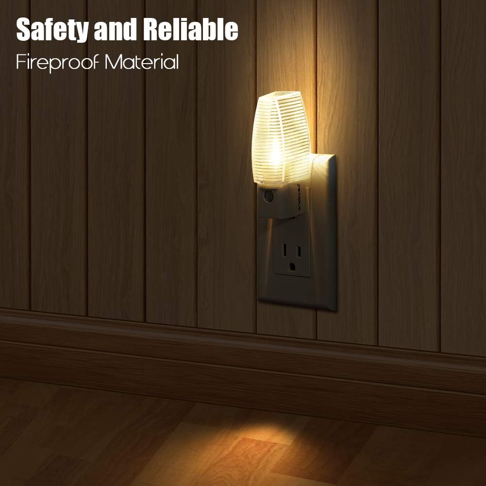 A close-up image of the Emotionlite night light plugged into a wall outlet, emitting a warm glow. The surrounding wall is made of wooden panels, highlighting its use in a home environment.