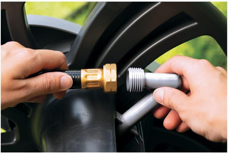 Close-up of hands connecting a garden hose with brass fittings to the hose reel's water inlet.