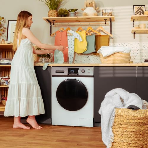 Mujer usando la lavadora Cecotec Bolero Dresscode en una habitación con ropa seca colgante, destacando su funcionalidad y estilo.