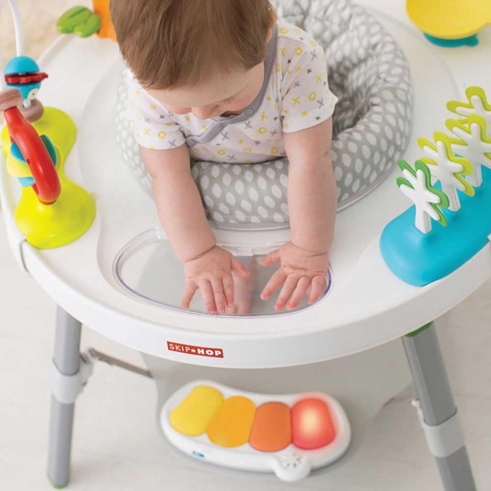 Skip Hop - Mesa de actividades escalable y rebote - Bebé de 4 meses y más - Juego de despertar para aprender a caminar - Asiento giratorio 360° rebotando + 25 actividades - Hebillas para atar juguetes