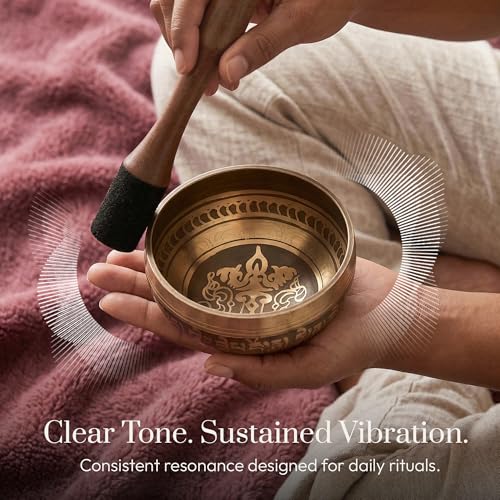 Tibetan singing bowl resting on a cushion beside a wooden mallet.