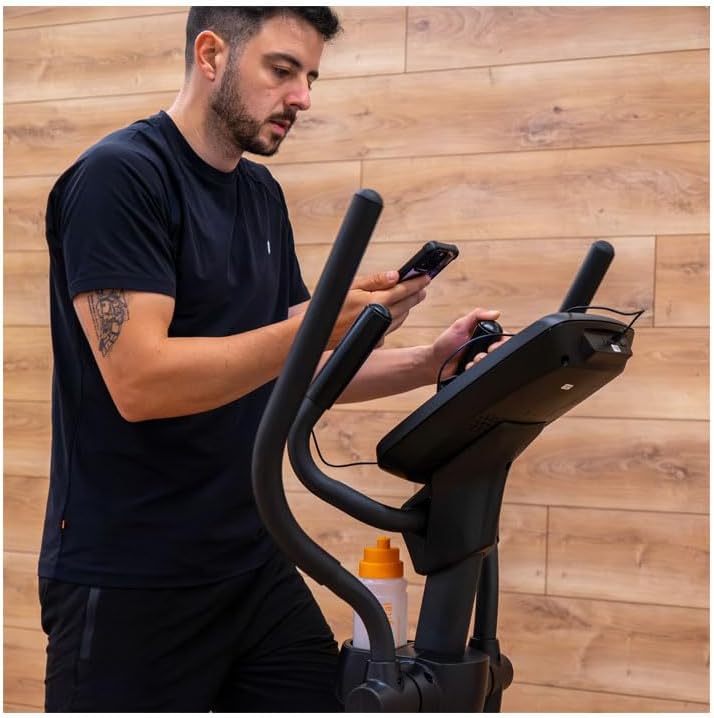 Person tilting the BH i.Quantum II elliptical trainer to move it using the transport wheels.