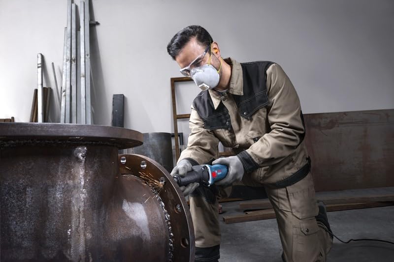 Worker using Bosch GGS 5 LS straight grinder on a large metal flange, kneeling