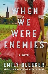 Book Cover When We were Enemies, the back of a young woman in a red dress carrying a suitcase and walking town a church. 
