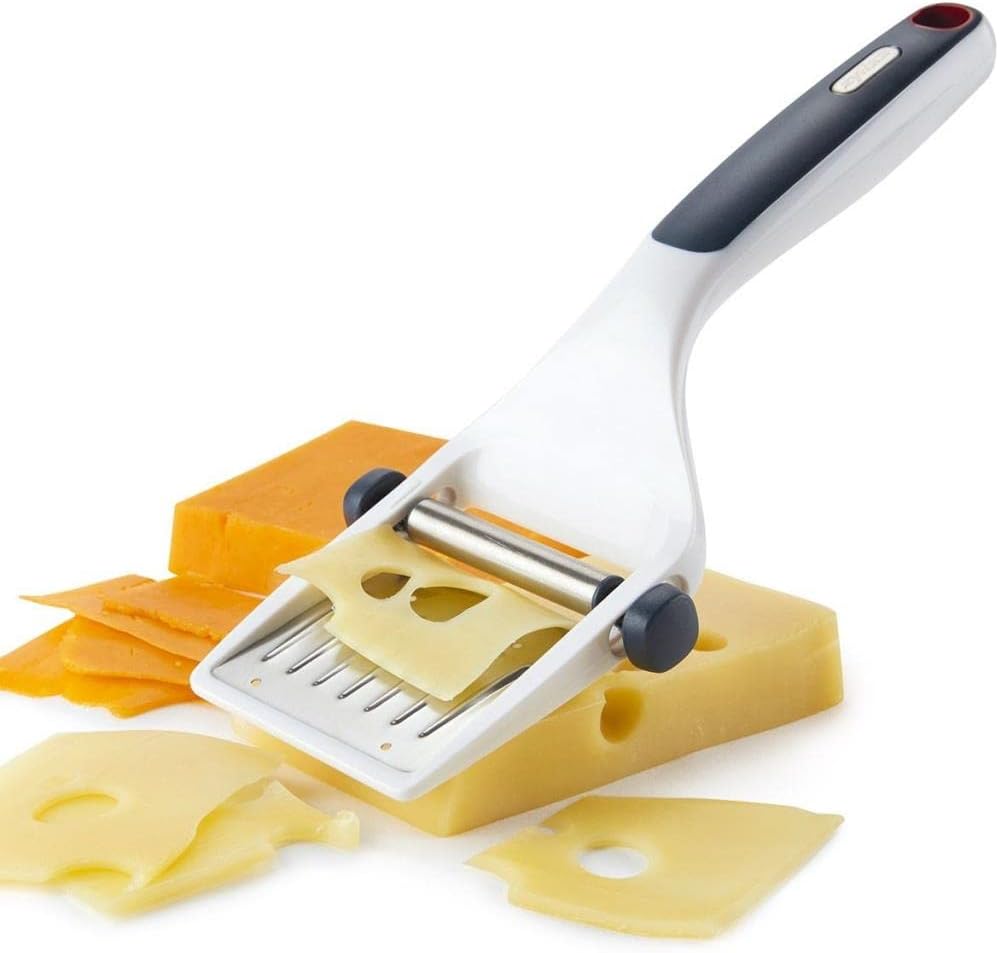 The Zyliss cheese slicer in action, slicing a block of cheese into thin pieces.