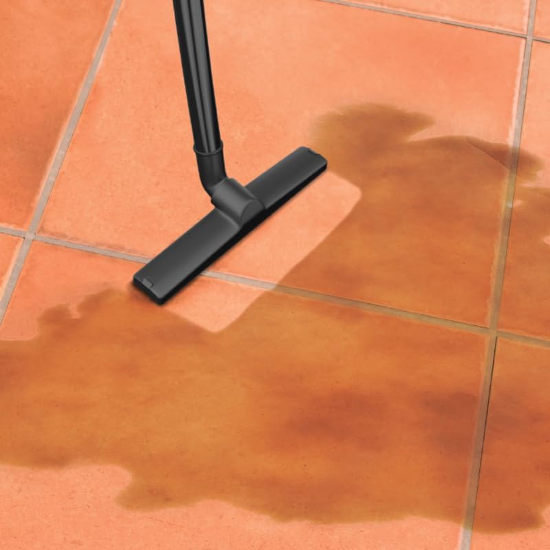 Vacuum cleaner nozzle cleaning a wet spill on tiles