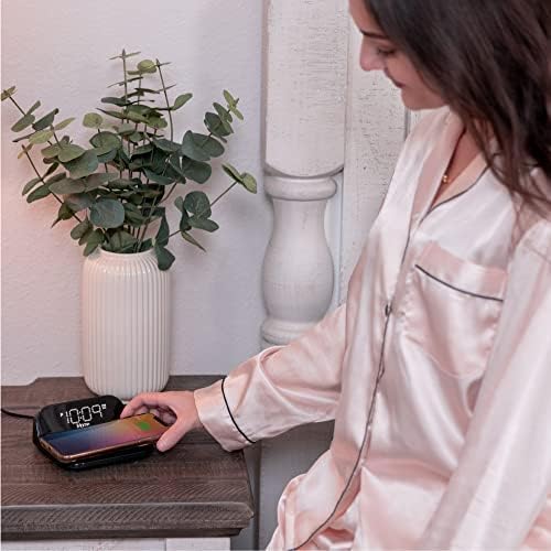 iHome Alarm Clock with Wireless Charging on a nightstand with a phone charging