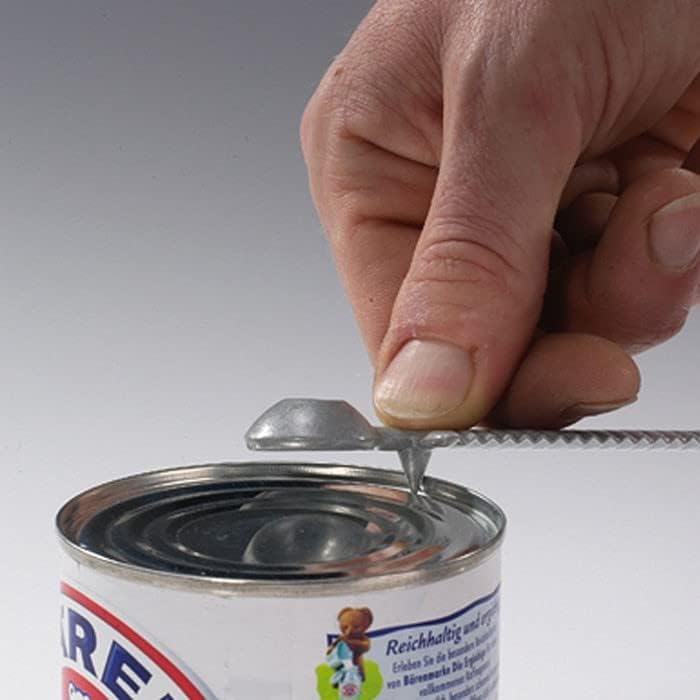A hand using the Westmark Decorex Spezial tool to pierce a can.