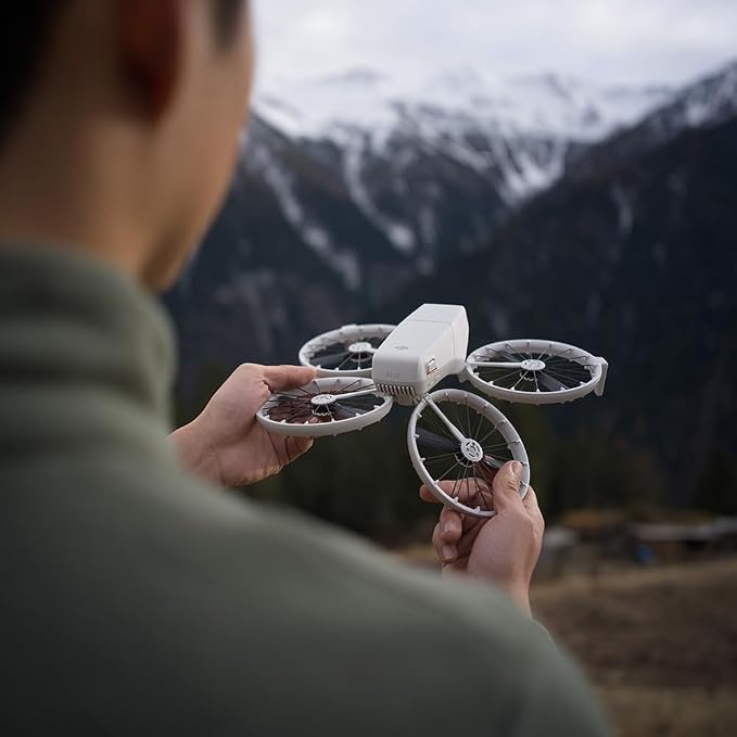 Pessoa segurando o drone compacto DJI Neo com as duas mãos, mostrando seu tamanho reduzido em meio a uma paisagem montanhosa.