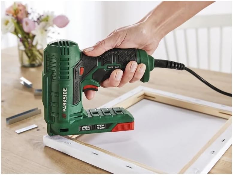 A person using the PARKSIDE PHET 15 C2 Electric Stapler to fasten fabric to a wooden frame, demonstrating one-handed operation.