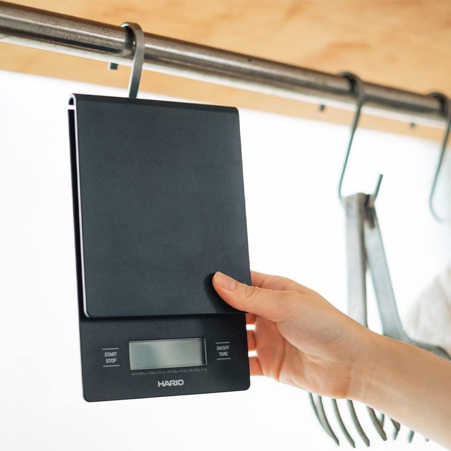 HARIO VSTN-INT-2000B V60 Drip Coffee Scale being held by hand, showing its compact size