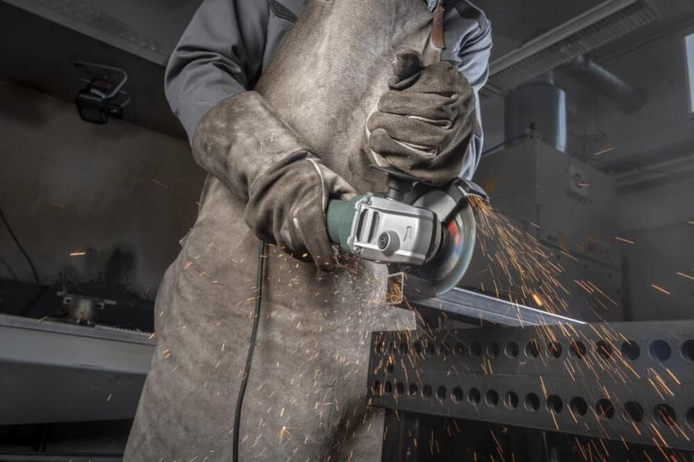 Close-up of a person using an angle grinder, focusing on the sparks and the tool