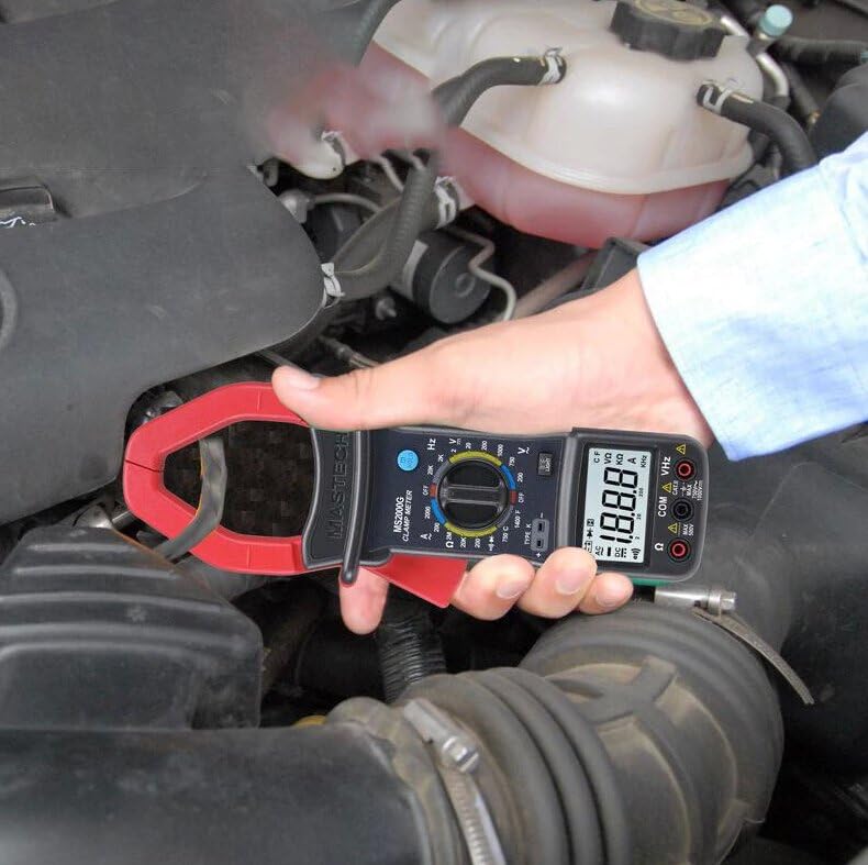 A hand holding the Mastech MS2000G Digital Clamp Meter, demonstrating its use to measure current around an electrical cable in an engine bay.