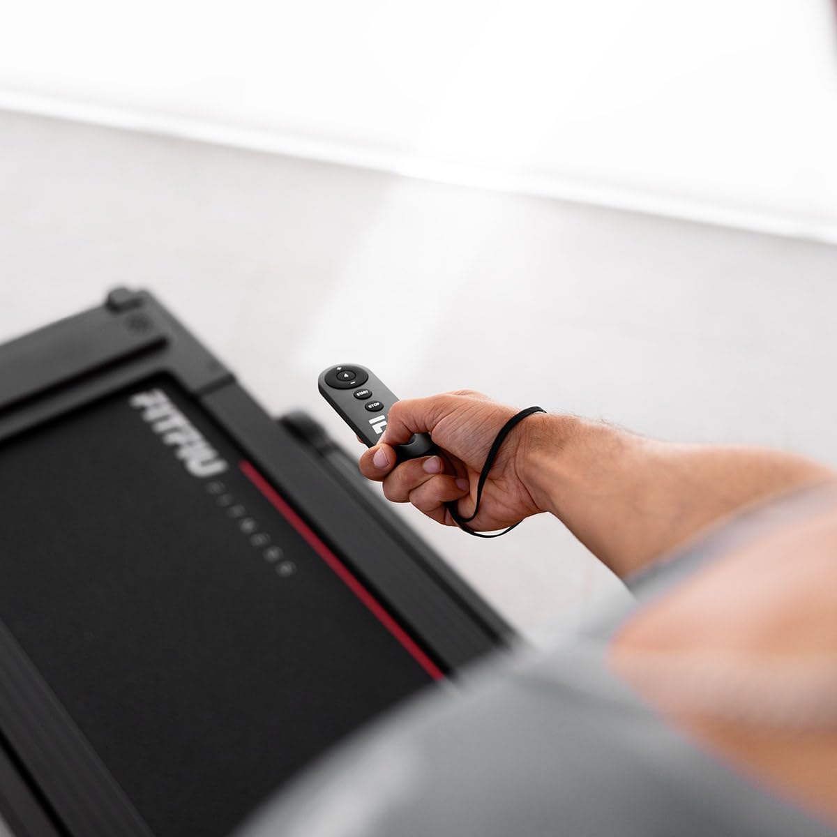 Close-up of the remote control for the treadmill, showing buttons for start, stop, speed adjustment, and program selection.